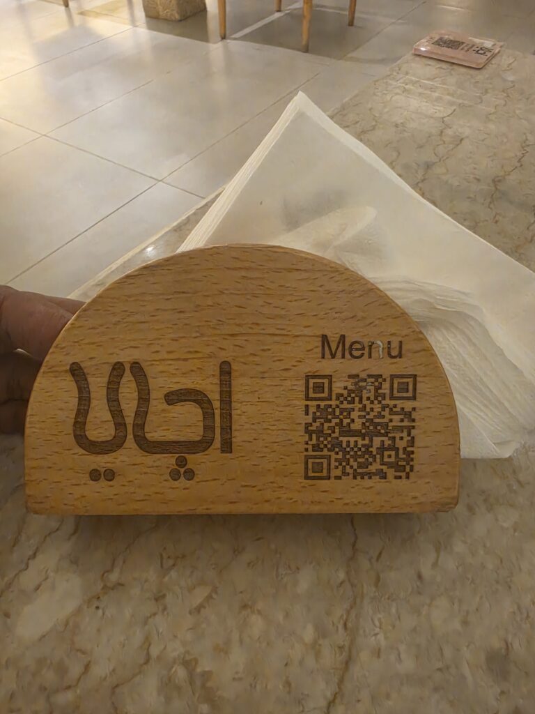 حامل المناديل الخشبي المحفور عليه شعار مطعم أچاي وباركود المنيو الرقمي